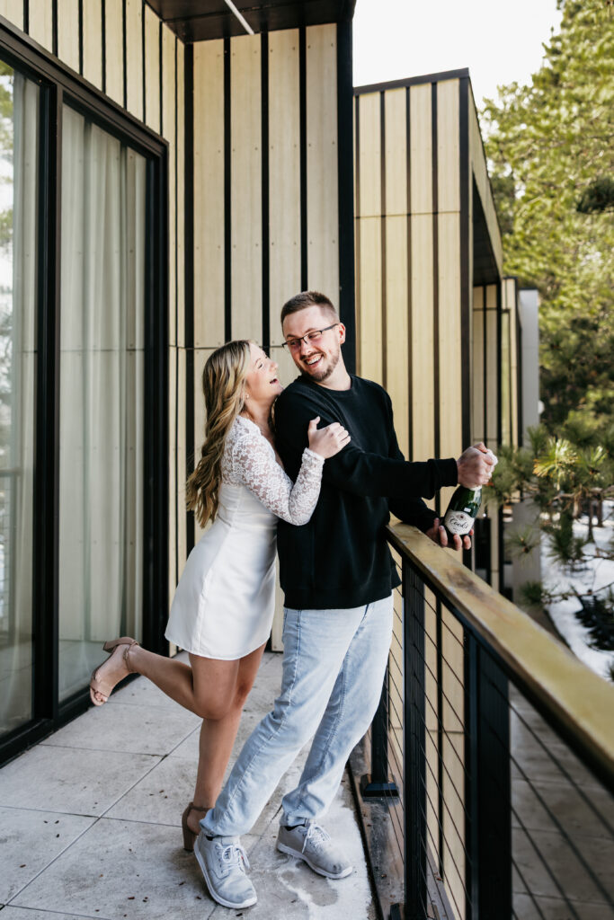 Engagement couple popping a bottle of champagne during their photoshoot at Catalyst by Nature Link